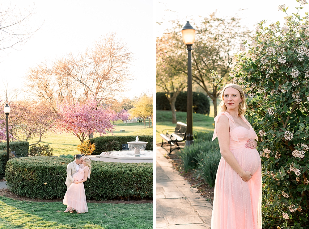 A pregnant woman wearing a pink dress embraces her husband during their Baker Park maternity photos in Frederick, Maryland.