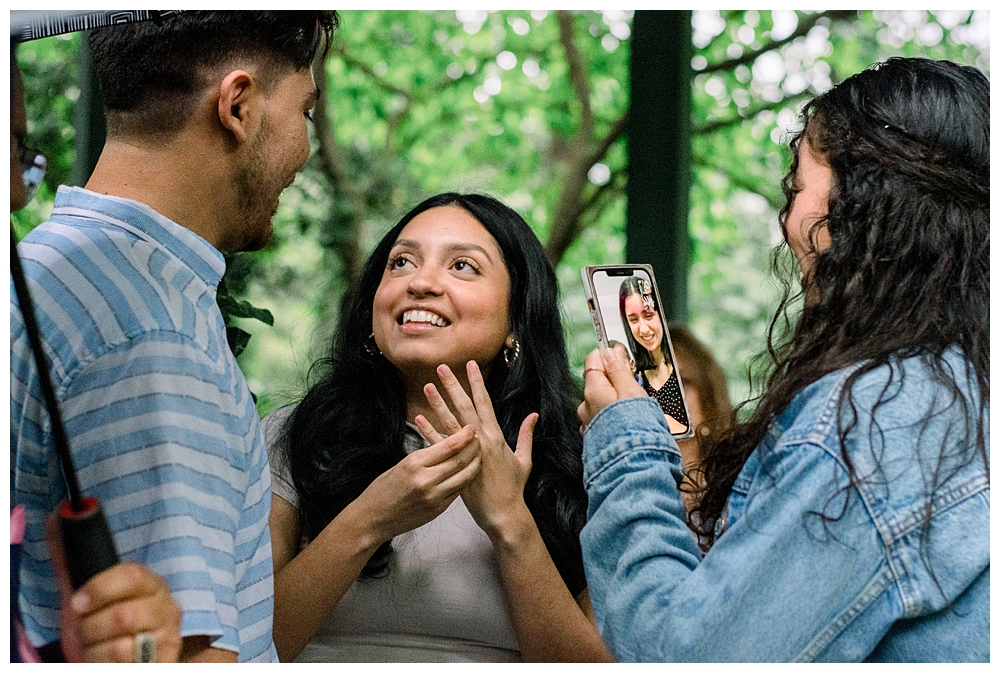 A recently engaged woman shows off her ring after a surprise proposal at McCrillis Gardens in Bethesda, Maryland.