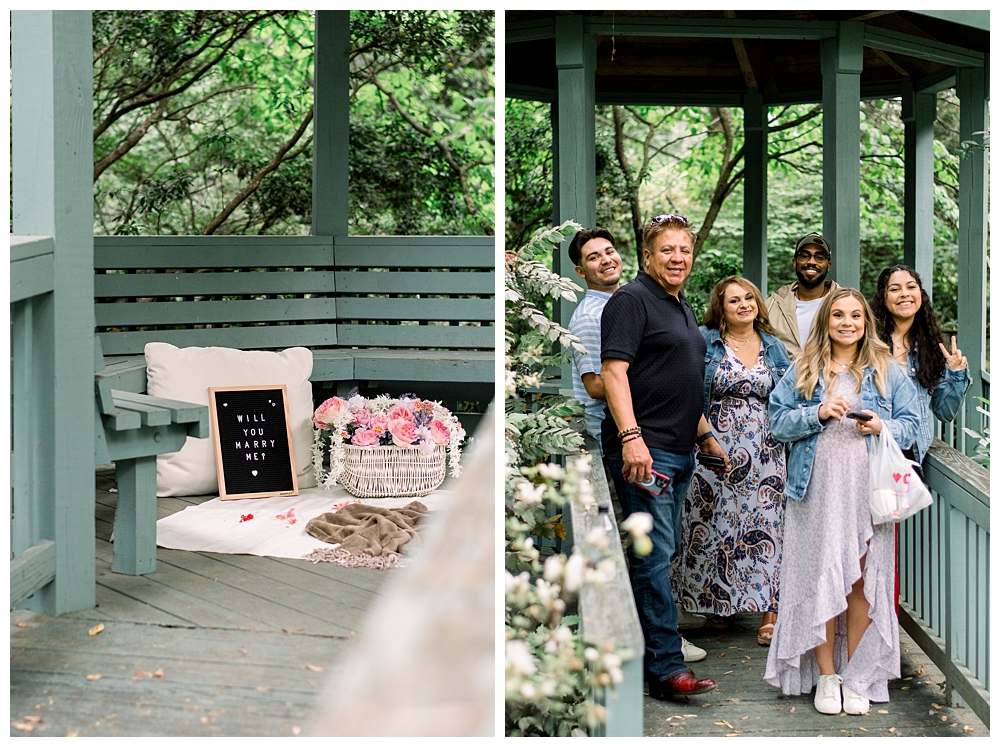 A group of friends and family stand with a recently engaged couple after a surprise proposal at McCrillis Gardens in Bethesda, Maryland.