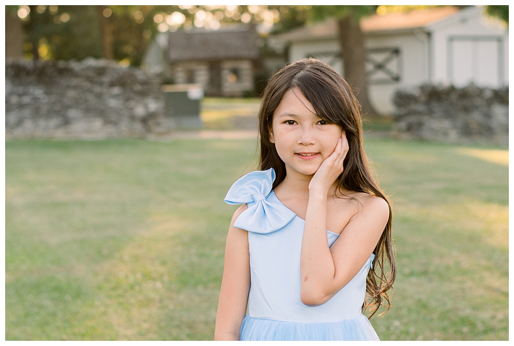 A young girl stands in front of a barn during a family photo session at Rose Hill Manor in Frederick, Maryland.